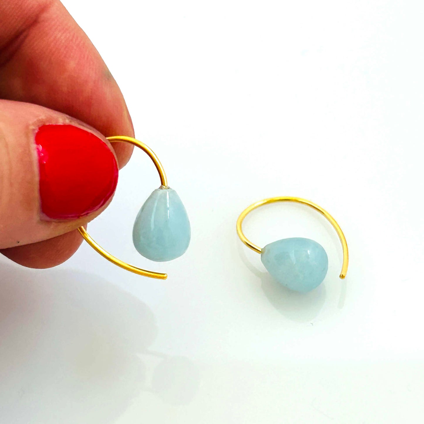 Detailansicht eines Aquamarin-Ohrhängers in Tropfenform, Bügel in glänzendem Gold